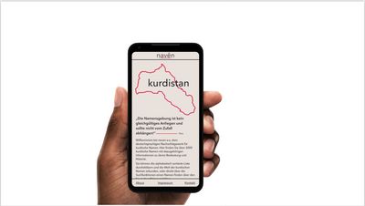 Hand hält Smartphone mit Website. Oben der Umriss Kurdistans mit Überschrift: Kurdistan. Darunter Fließtext