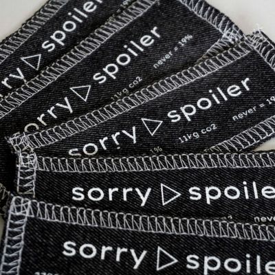 Fünf schwarze Aufnäher mit weißer Schrift: sorry spoiler